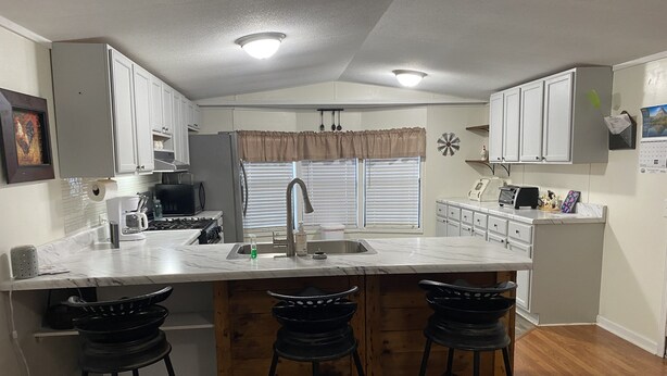 A compact kitchen with a central island, bar stools, a microwave, and a coffee maker.
