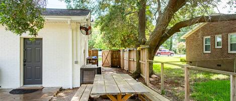 A picnic table with benches, a small building with a door, and a wooden fence.