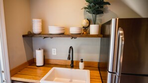 A kitchen with a stainless steel refrigerator, a sink, wooden countertops, and shelves with bowls and a globe. - Clean, Private Guesthouse-9 min. to Downtown Charleston, 15 min. to FollyBeach! (Charleston)