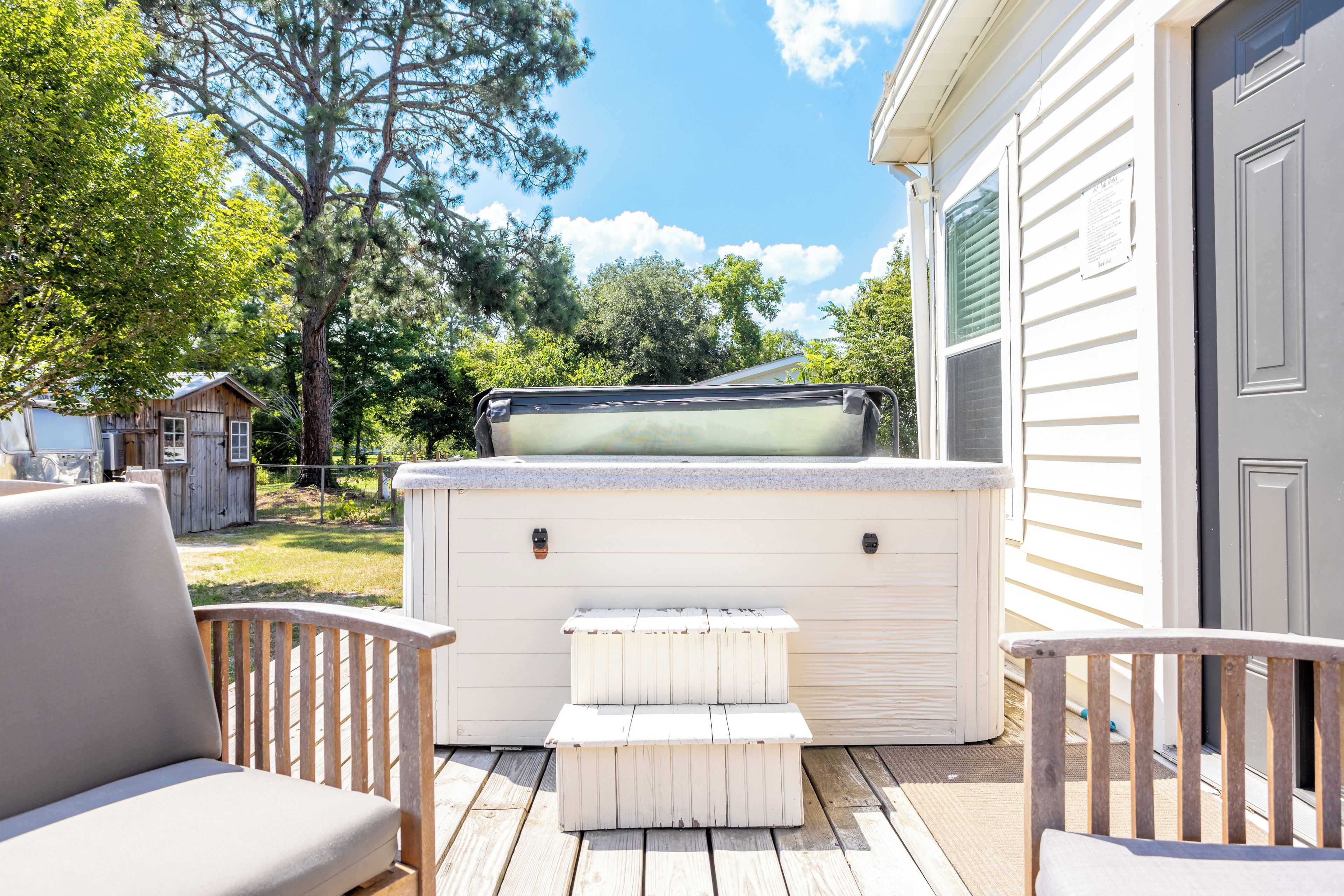 A deck with outdoor seating, a hot tub, and a wooden shed in the background.