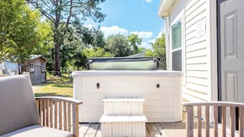 A deck with outdoor seating, a hot tub, and a wooden shed in the background.