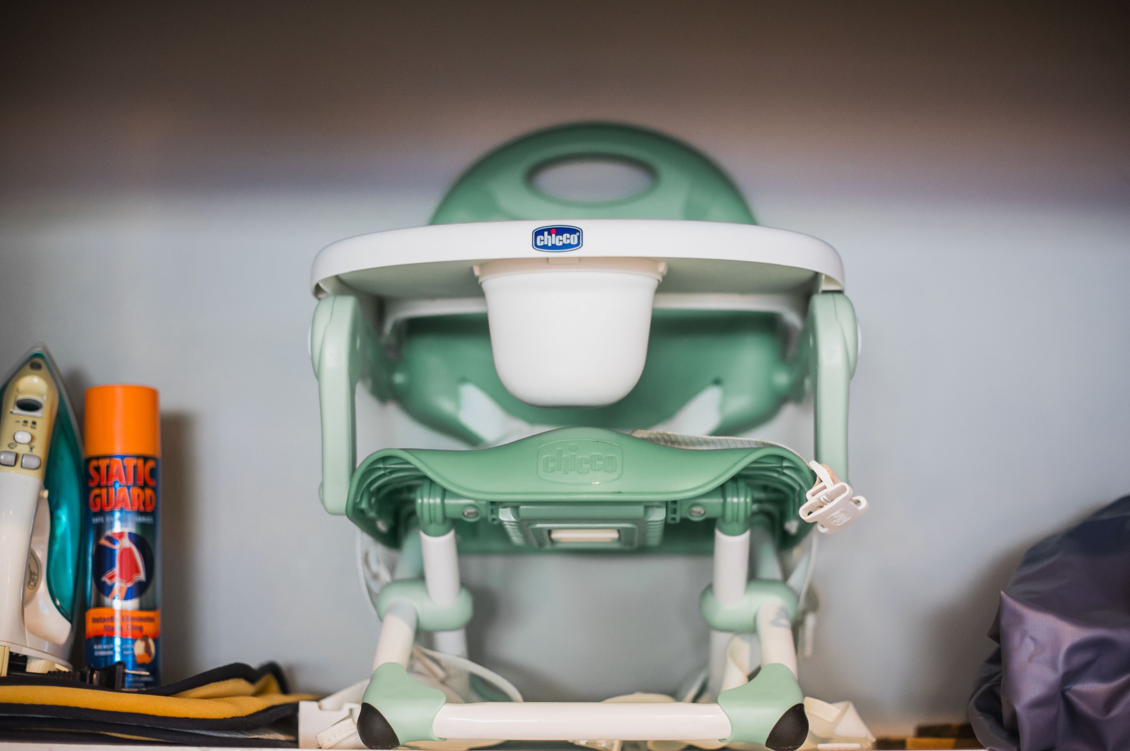 A green and white baby changing station with a "Chicco" label, a "Static Guard" spray can, and a baby bottle.