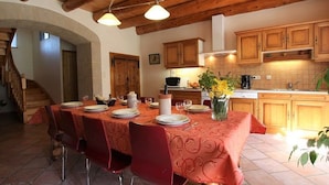 A dining area with a red tablecloth, wooden chairs, and a chandelier. - Restored farmhouse with enclosed garden and terrace, near Puy en Velay (Le Monastier-sur-Gazeille)