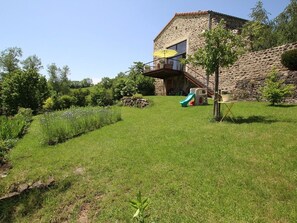 A stone house with a balcony, a slide, and a garden.