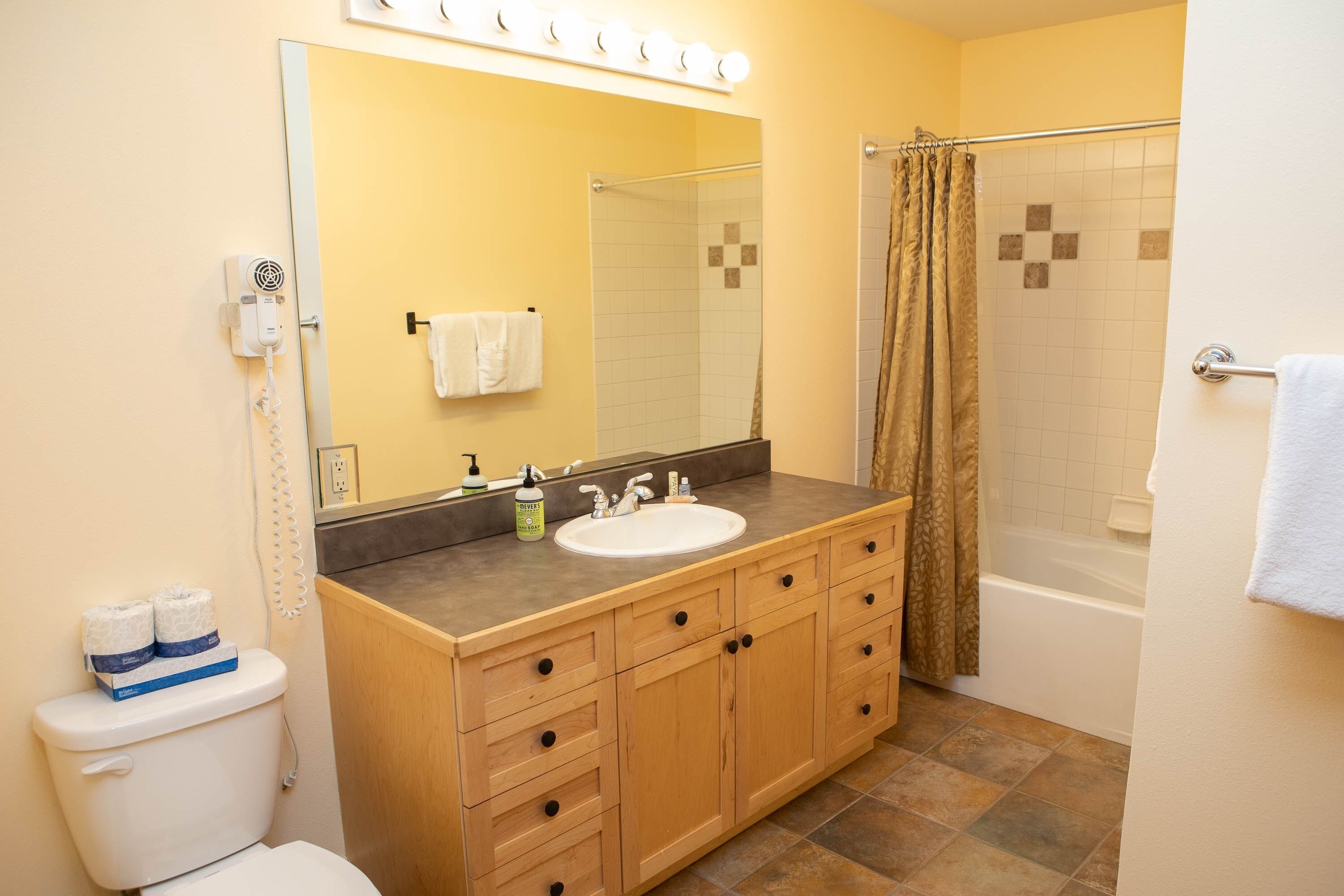 A bathroom with a wooden vanity, white sink, and a shower with a glass door.