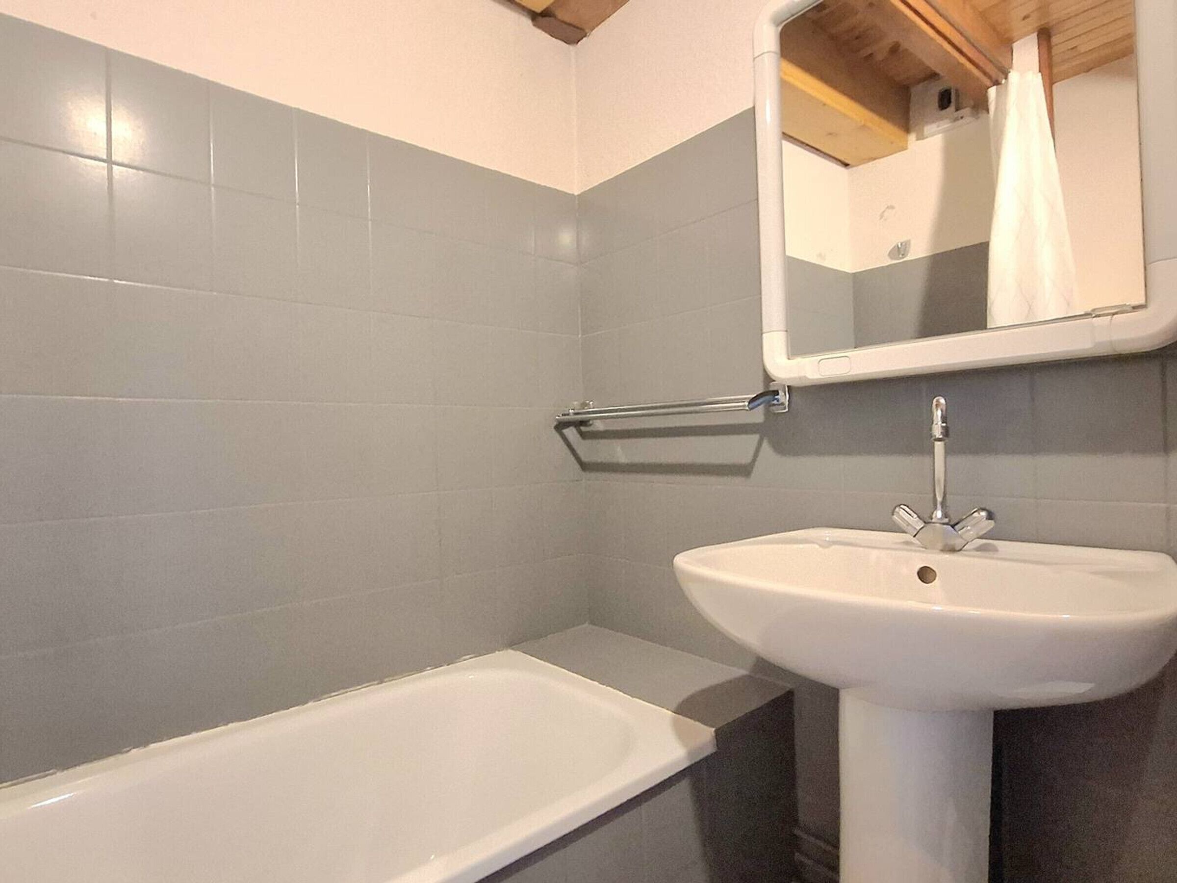 A bathroom with a bathtub, a sink, and a mirror.