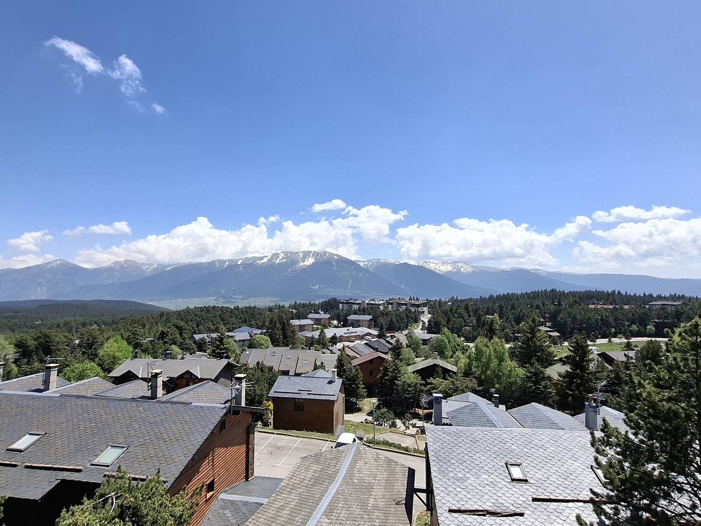 Zona residencial amb cases, cel serena i muntanyes nevades al fons.