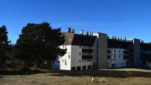 A multi-story residential building with a flat roof and multiple chimneys. - Cozy 2-Room Apartment with Cabin for 6, Near Shops and 800m from Ski Slopes (Bolquère-Superbolquère)