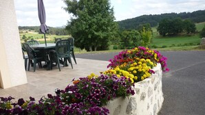 A patio area with outdoor seating and a flower bed. - Cottage with private terrace and garden in Saugues, all inclusive (Saugues)
