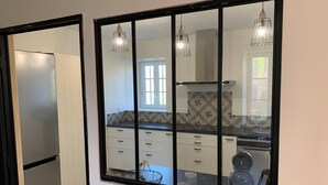 Eine Küche mit einem großen Fenster, weißen Schränken und einer schwarzen Arbeitsplatte.