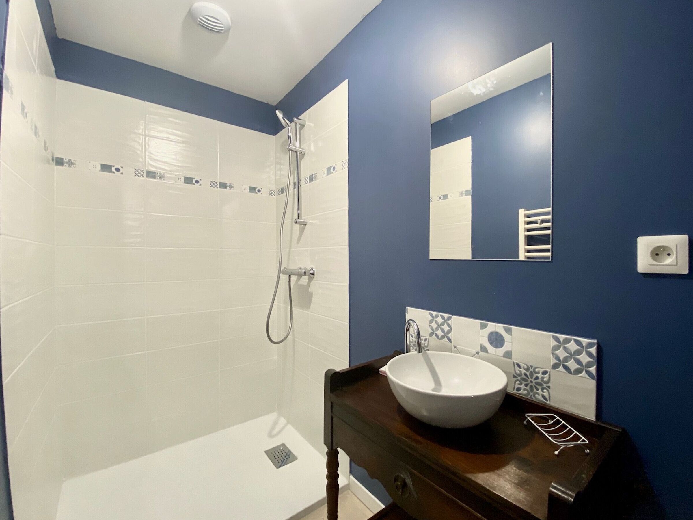 A bathroom with a white bathtub, a shower, a sink with a white basin, and a mirror on the wall.