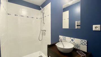 A bathroom with a white bathtub, a shower, a sink with a white basin, and a mirror on the wall.
