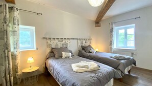 Ein Schlafzimmer mit zwei Betten, einer Lampe und einem Fenster.