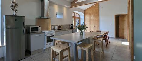 Une cuisine moderne dotée d’un îlot central, de poutres en bois et d’une verrière.