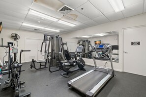 Uma academia com diversos equipamentos de exercício, incluindo esteiras, aparelhos de muscula ção e uma bicicleta ergométrica.