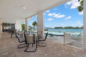 A covered outdoor area with a pool, lounge chairs, and a view of the water.