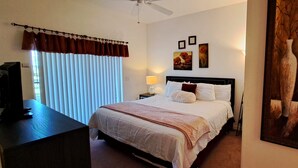 Une chambre d’hôtel avec un lit, un bureau, une télévision et un tableau au mur.