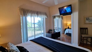 Ein Hotelzimmer mit Bett, Wandfernseher, Stuhl, Schreibtisch und einem Balkon mit Blick ins Freie.