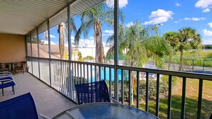 Ein Balkon mit Glasgeländer, blauen Stühlen und einem Tisch.