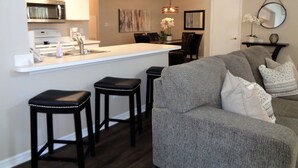 A modern kitchen with a central island, bar stools, and a dining area with chairs.