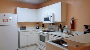 Cocina compacta con alacenas blancas, un microondas, estufa y lavamanos.