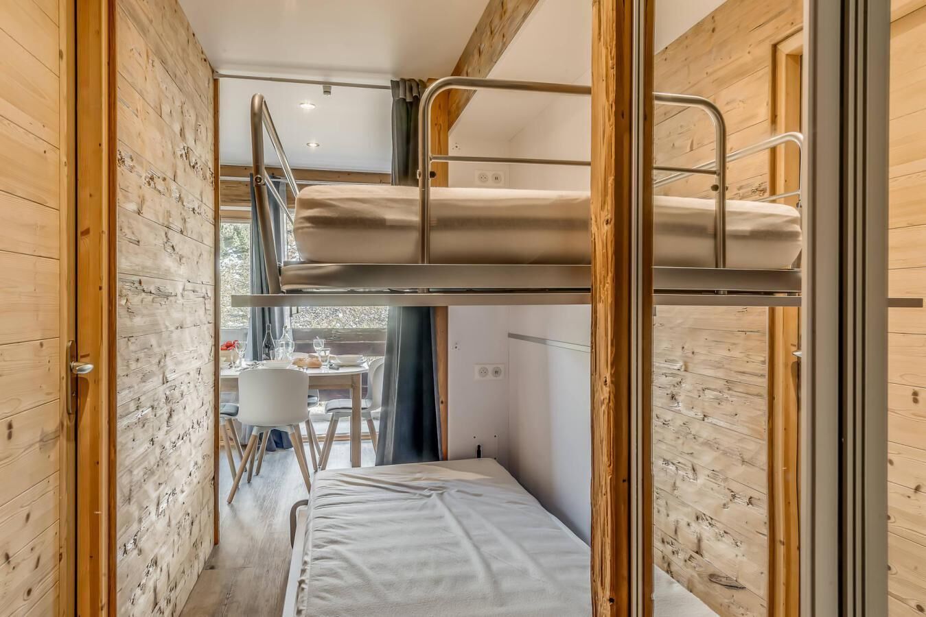 Una habitación pequeña con literas, una mesa de comedor y una ventana.