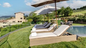 A poolside area with lounge chairs and umbrellas, a stone building in the background, and a clear sky. - Luxury-Villa, Tuscany-Villa, Private Swimming Pool-Villa (Panzano In Chianti)