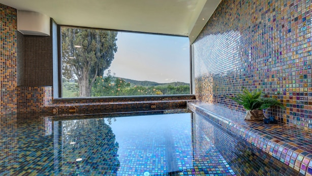 An infinity pool with mosaic tiles, a large window, and a view of greenery. - Luxury-Villa, Tuscany-Villa, Private Swimming Pool-Villa (Panzano In Chianti)