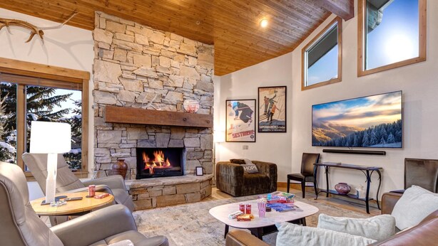 A cozy living room with a stone fireplace, leather furniture, and a large TV.