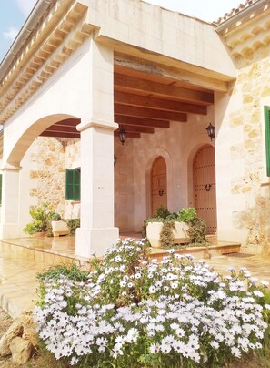 A building with a covered entrance, stone walls, and green shutters. - Spectacular Villa in Sencelles (sencelles)