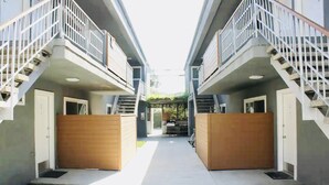 A corridor with two-story buildings, wooden gates, and a bike parked in the middle. - 1BR Apt in Culver City by Just Bring Your Toothbrush (Culver City)