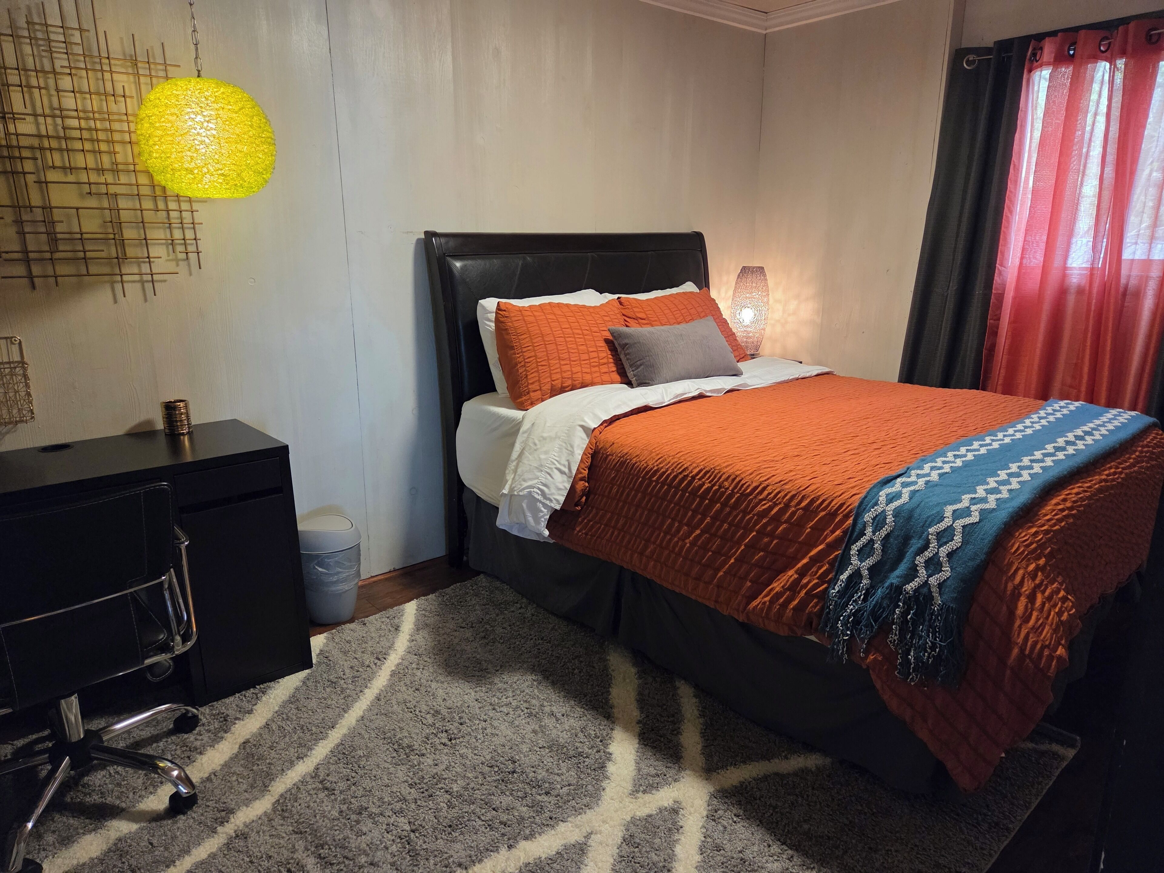 A neatly arranged bedroom with a bed, a desk, and a chair.
