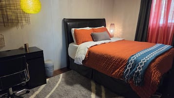 A neatly arranged bedroom with a bed, a desk, and a chair.