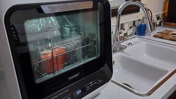 A compact kitchen with a built-in dishwasher, a sink, and a window providing natural light.