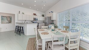 A modern kitchen with white cabinets, a central island, and bar stools.