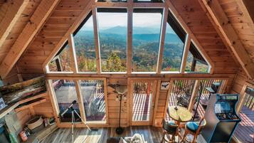 A wooden cabin with a large skylight, a telescope, a gaming table, and a cozy seating area.