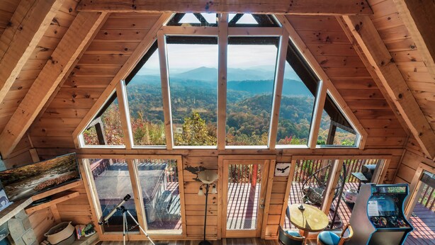 A wooden cabin with a large skylight, a telescope, a gaming table, and a cozy seating area.