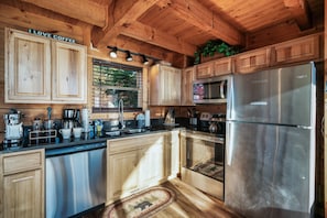 Cocina de cabaña de madera con un refrigerador de acero inoxidable, cafetera y armarios de madera.