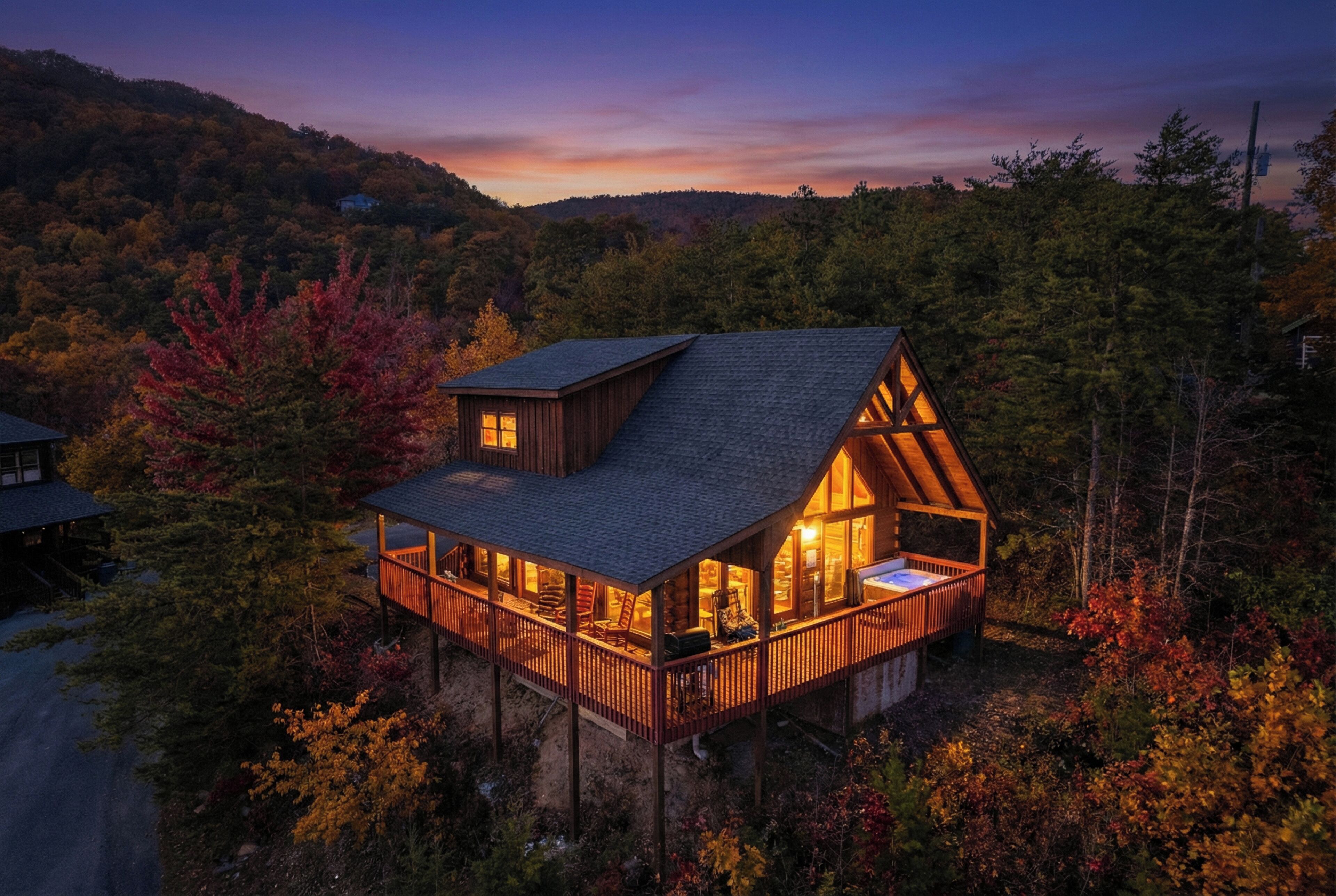 A wooden cabin with a balcony, surrounded by autumn foliage.
