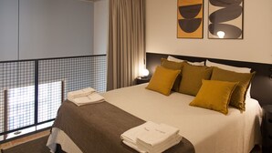 A hotel room with a bed, a balcony, and two abstract paintings on the wall.