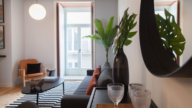 A modern living room with a sofa, a coffee table, and a large mirror.