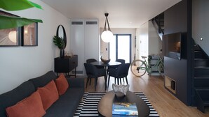 A modern living room with a sofa, coffee table, and a dining area with chairs and a table.