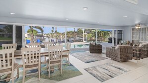 A spacious indoor area with a pool, wicker furniture, and a sign reading "Welcome to Cape Coral." - Stunning Remodel, HEATED POOL, Brand New Furnishings, Full Canal Sunset View (Cape Coral)