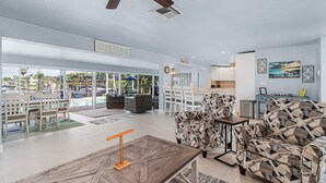 A spacious living area with a pool view, a ceiling fan, and a dining area. - Stunning Remodel, HEATED POOL, Brand New Furnishings, Full Canal Sunset View (Cape Coral)