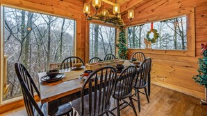 A wooden cabin dining area with a large table, chairs, and a chandelier. - Free Tickets | Wood Burning Fireplace, Hot Tub, WIFI, Pool Table, Sleeps 7 (Gatlinburg)