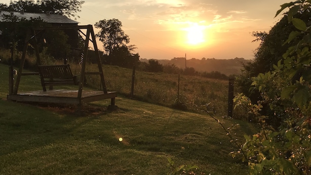 Un columpio de madera en un área verde, con un atardecer de fondo.