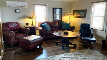 A living room with a brown leather sofa, a coffee table, a blue armchair, and a rug.