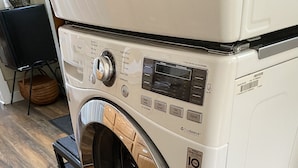 Una lavadora de carga frontal con puerta de acero inoxidable, un panel de control con diversas opciones y una etiqueta que dice 'TrueBalance'.