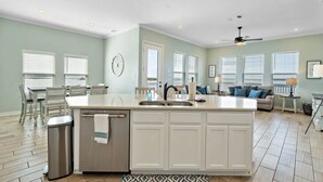 A spacious kitchen with a central island, a dining area with chairs, and a living room with a sofa and a lamp. - Bayfront Home with Scenic Views & Decks (Galveston)