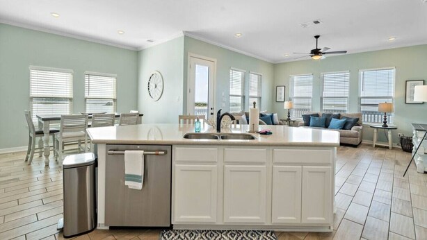 A spacious kitchen with a central island, a dining area with chairs, and a living room with a sofa and a lamp. - Bayfront Home with Scenic Views & Decks (Galveston)